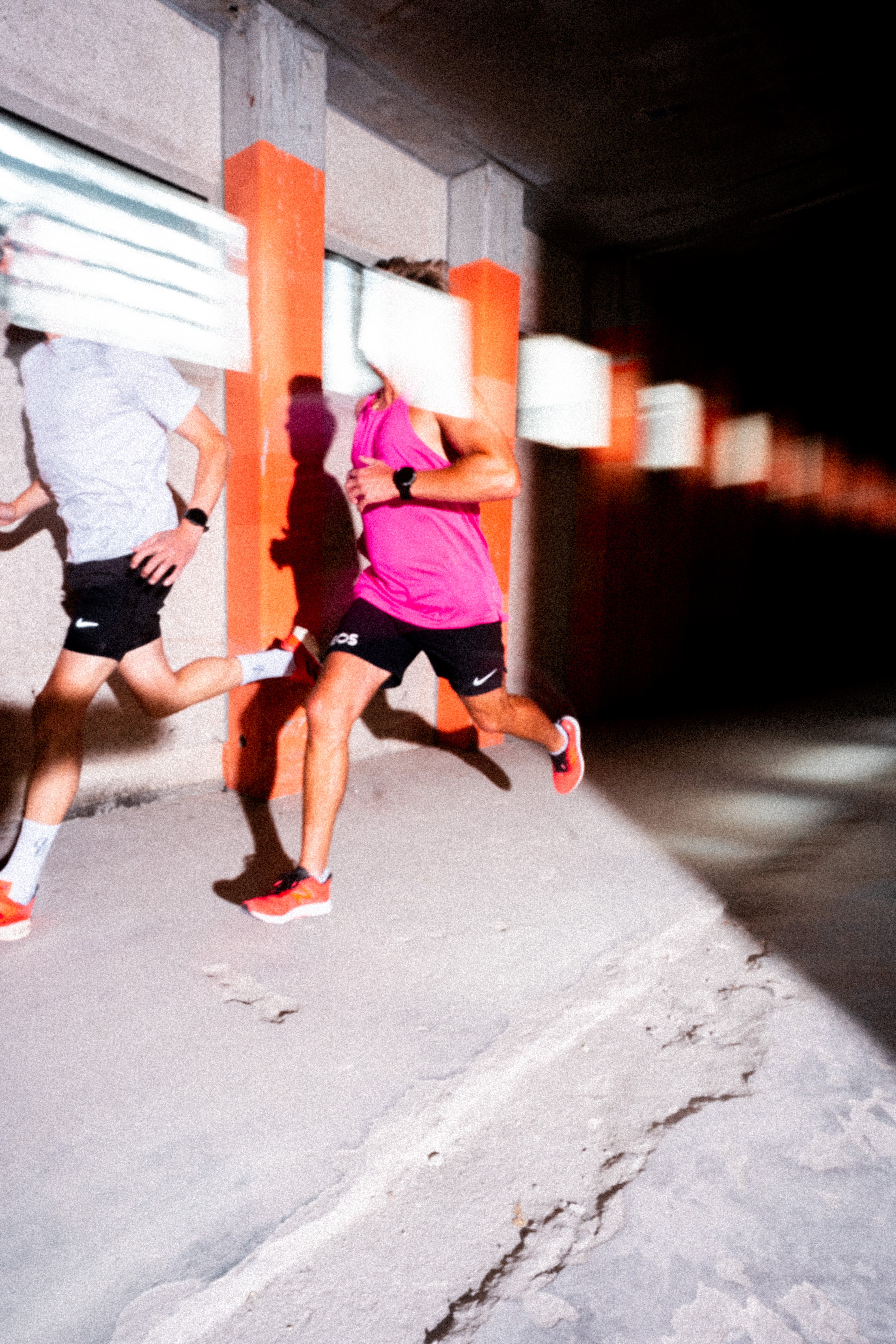 Runners in tunnel with orange pillars